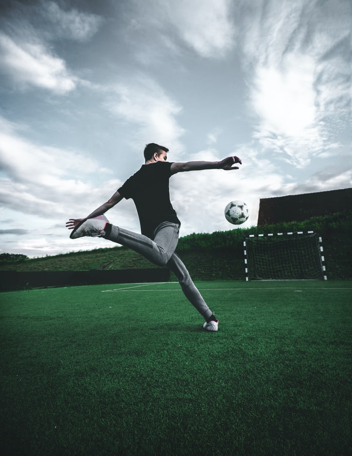 Soccer player training as he attempts to kick the ball into a small net