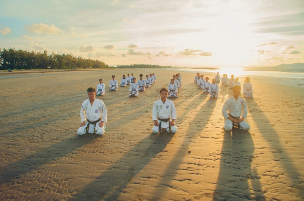 Tai Chi class kneeling in meditation on a beach