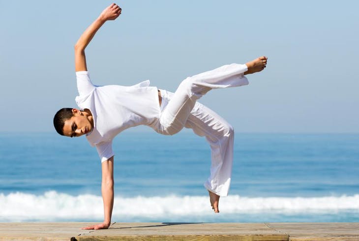 Capoeira instructor showcasing moves on a beach