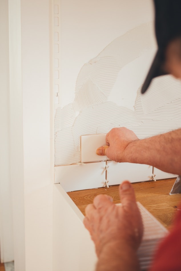 Handyman applying a backsplash tile to a wall