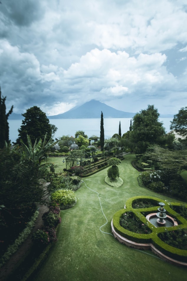 Beautifully landscaped backyard with water fountain and a view of a body of water and mountains