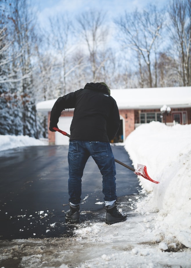 Snow remover shoveling a driveway