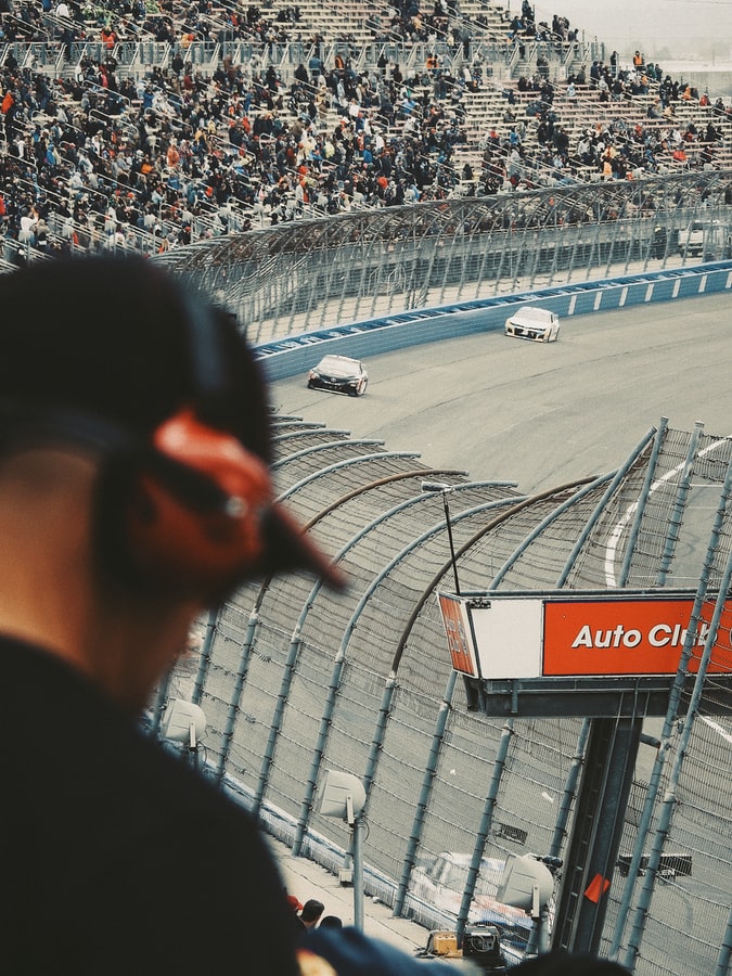 Racecar drivers approaching a turn in front of a crowd