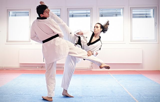 Taekwondo instructor demonstrating kicking moves with a partner