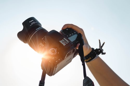 Landscape photographer holding up a camera to the sun